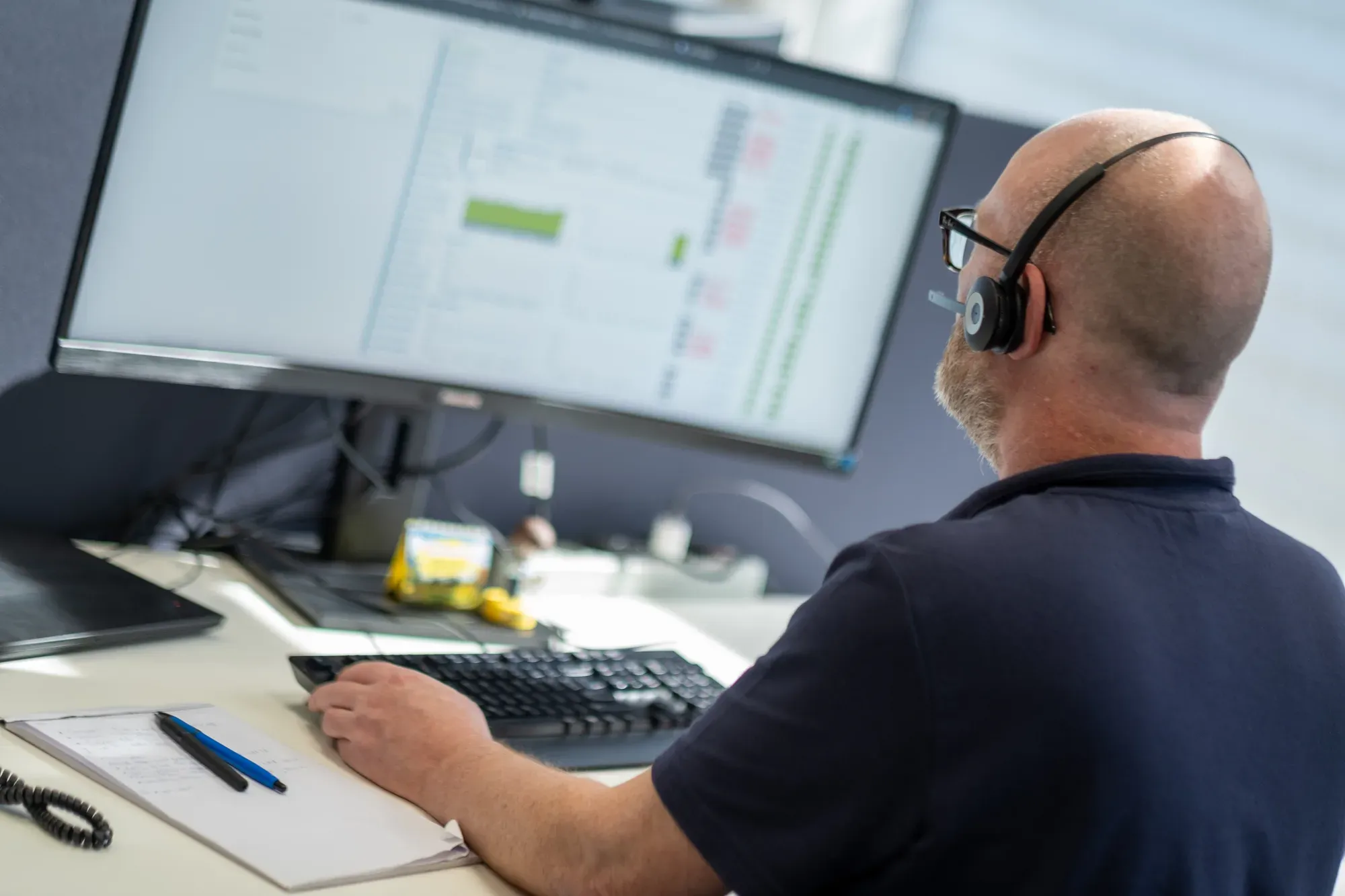 XSbyte-medewerker met headset aan het werk achter een beheerde werkplek